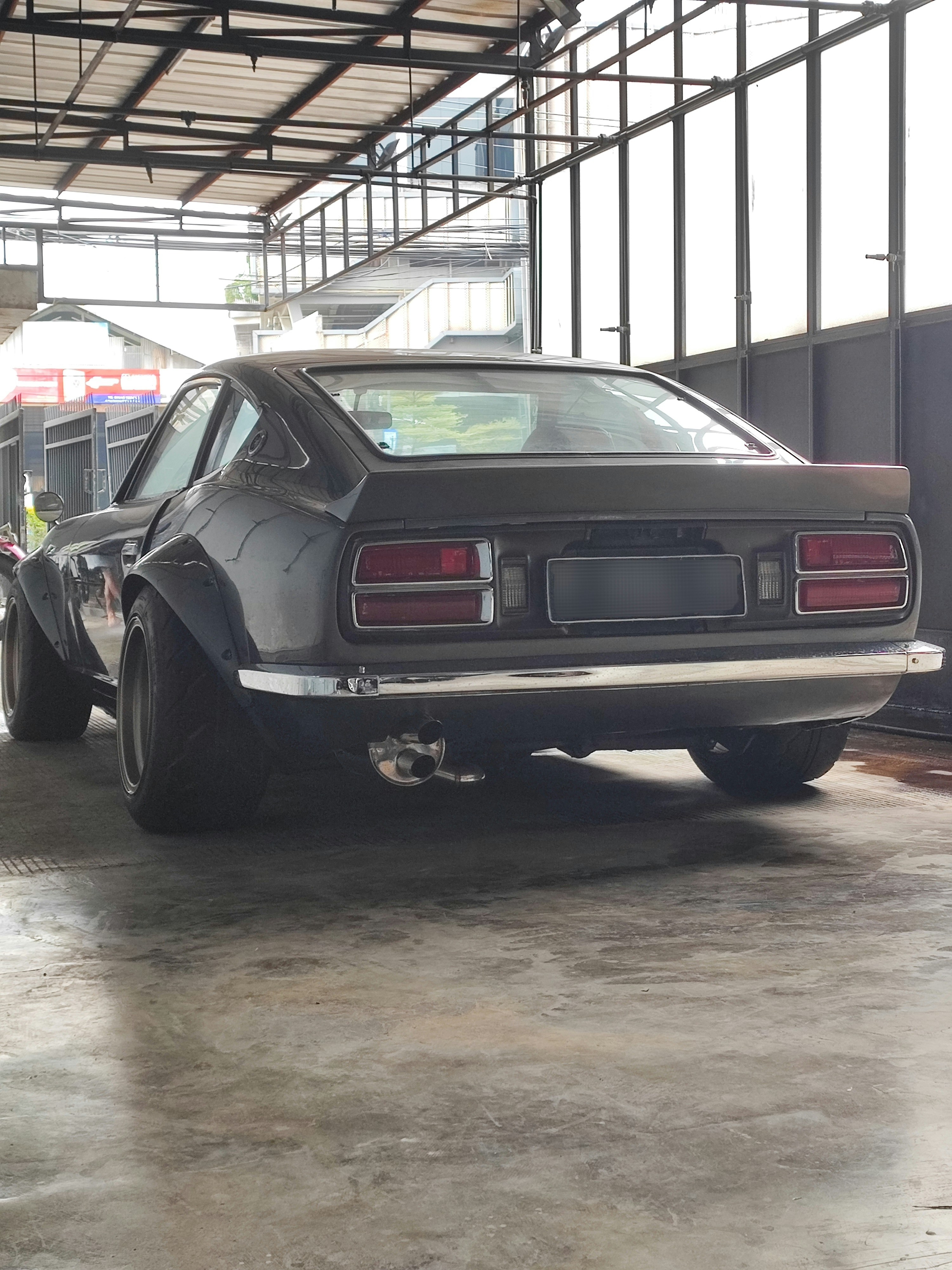 a black car parked in a garage next to another car