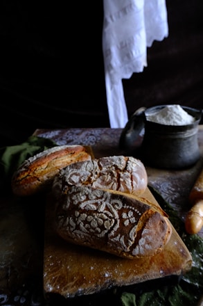 A warm, inviting kitchen counter with freshly baked bread and pastries arranged on rustic wooden boards.