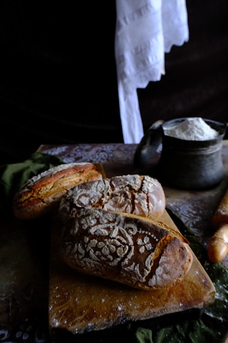 A warm bakery setting showing fresh bread and baking ingredients on a rustic wooden table.