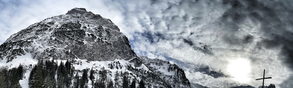 ein schneebedeckter Berg mit einem Kreuz im Vordergrund