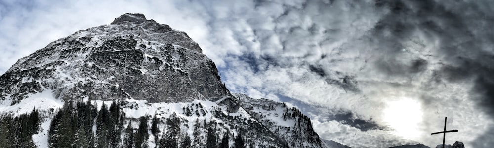 Una montagna innevata con una croce in primo piano