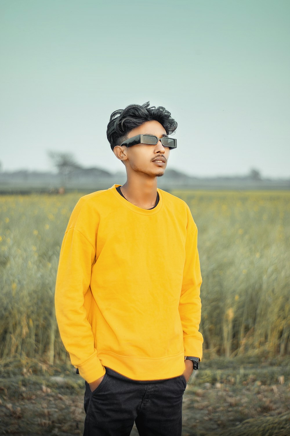 a young man standing in front of a field of tall grass