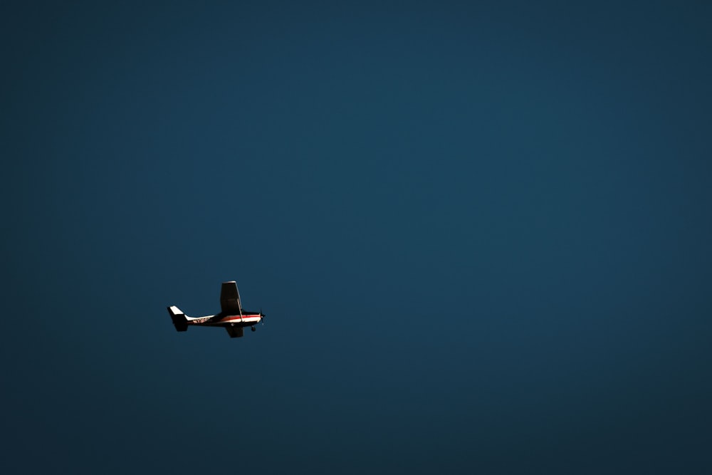 a small airplane flying through a dark blue sky