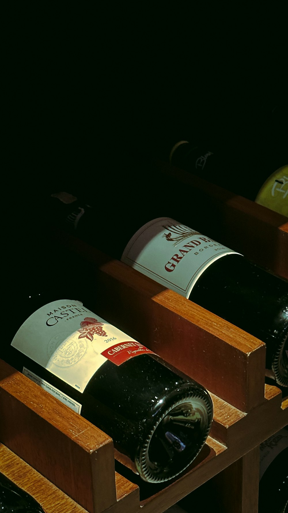 a row of wine bottles sitting on top of a wooden shelf