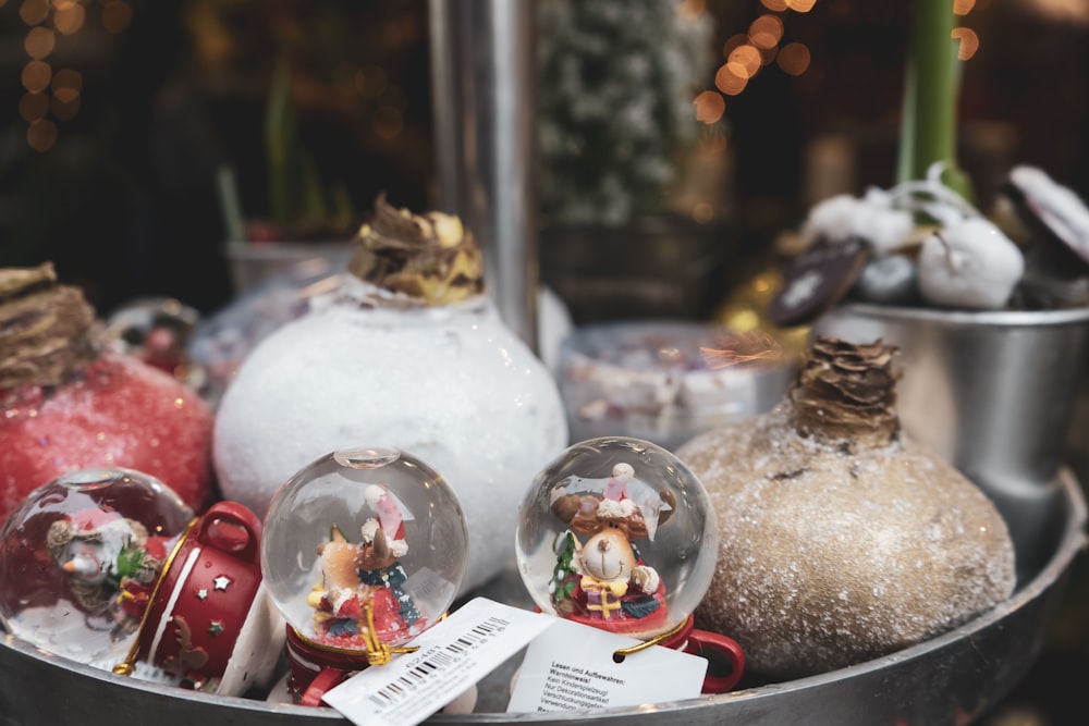 a metal bowl filled with snow globes and ornaments