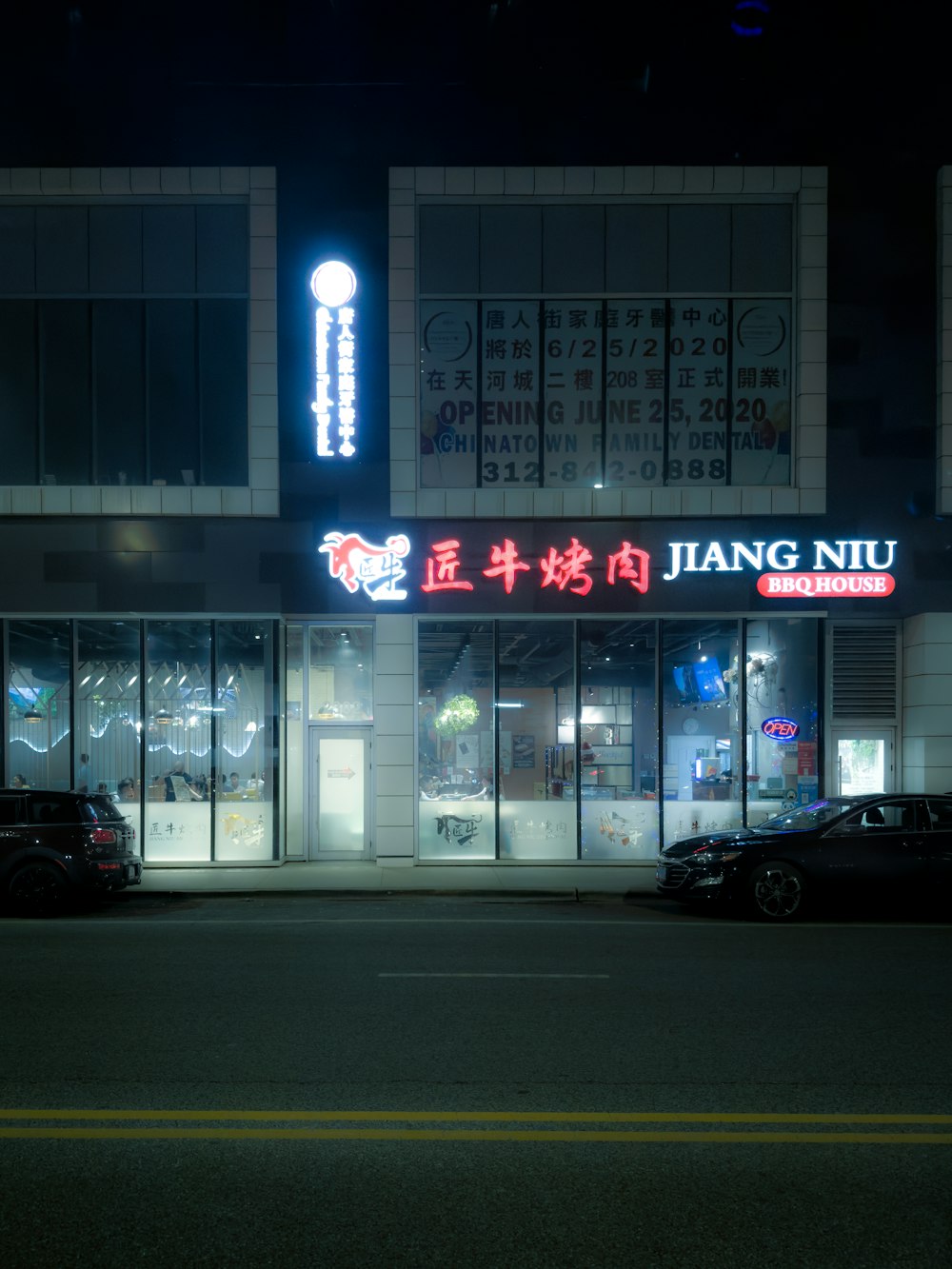 two cars parked in front of a building at night