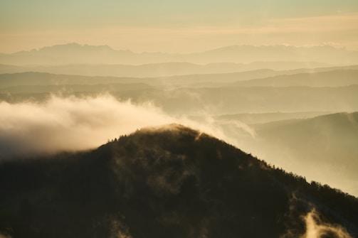 A misty mountain landscape at dawn with gentle light.