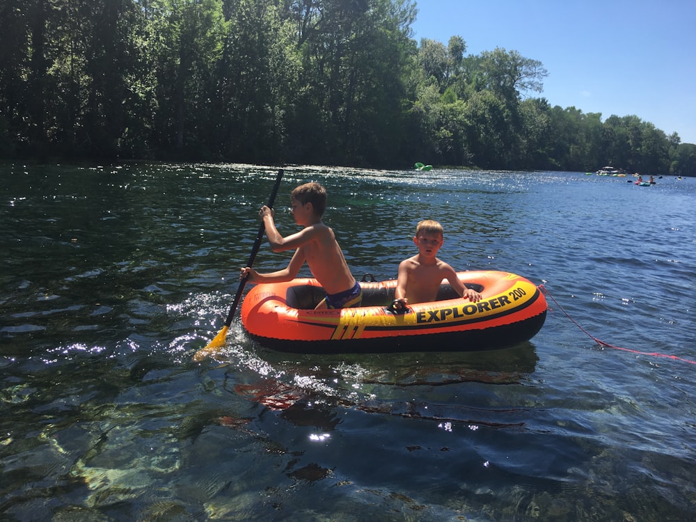 a couple of kids riding on top of an inflatable boat