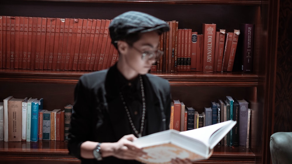 a man reading a book in front of a bookshelf