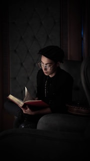 A thoughtful person reading a book on economics in a cozy setting.