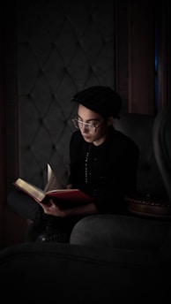 A thoughtful person reading a book on economics in a cozy setting.