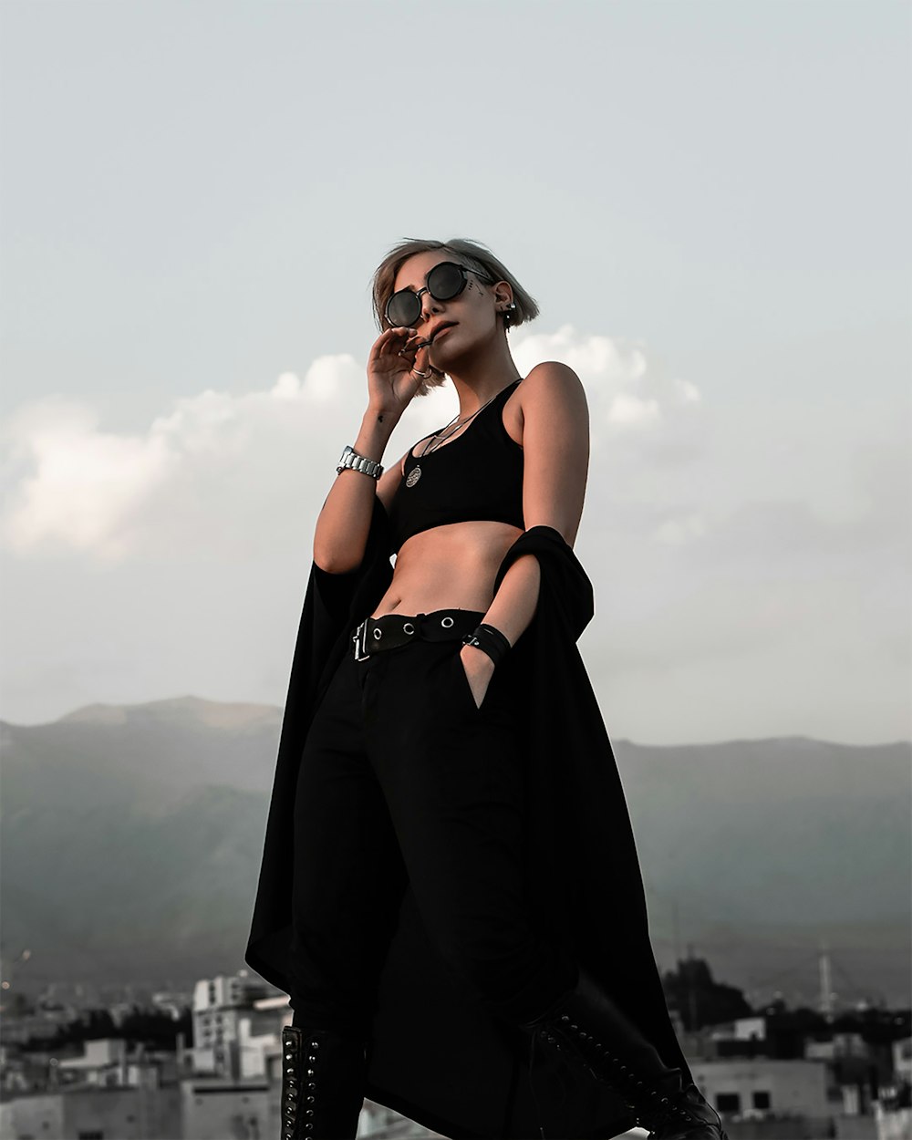 a woman in a black outfit and sunglasses talking on a cell phone