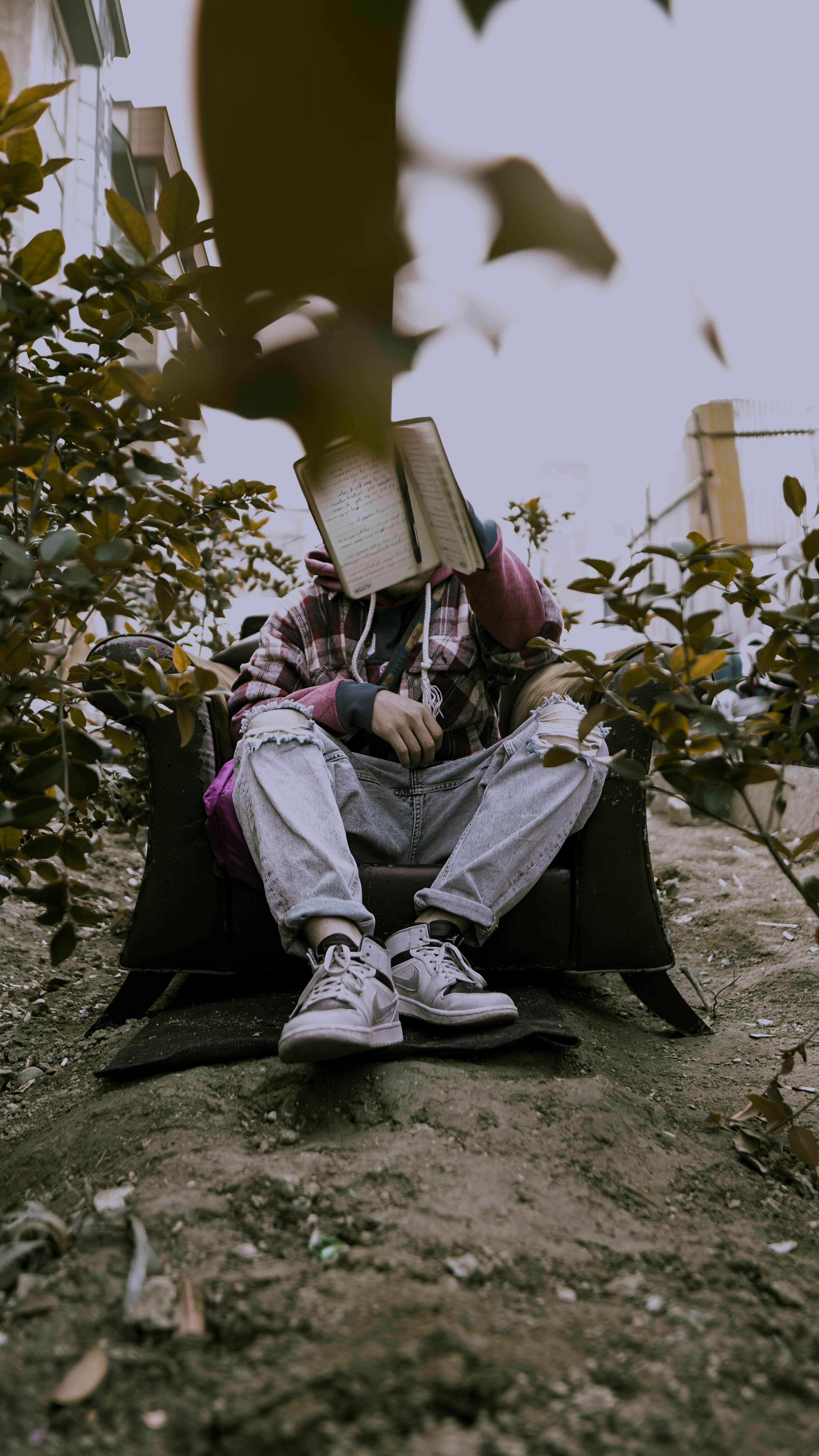Ein Mann sitzt mit einem Buch auf dem Kopf auf dem Boden
