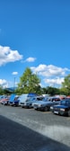 A row of modern cars parked in a bright outdoor lot under clear skies.