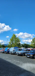 A friendly car dealership lot at Highway 60 Motor Sale with a variety of classic and exotic cars under a bright Minnesota sky.