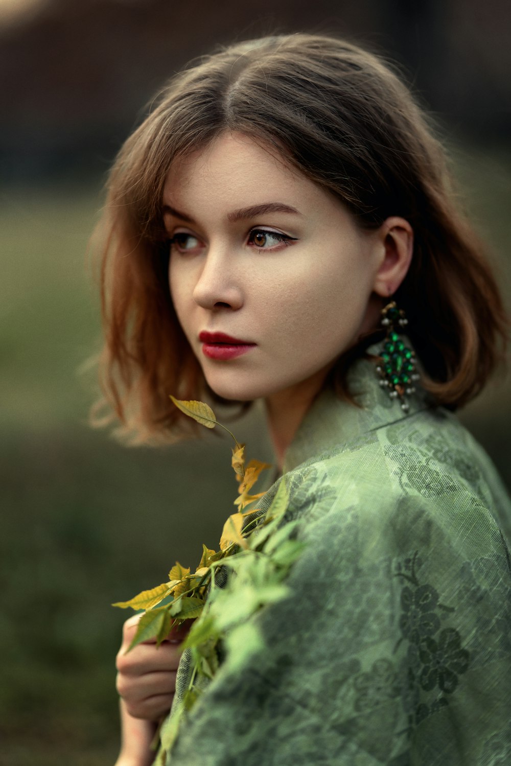 a woman in a green dress with leaves around her neck