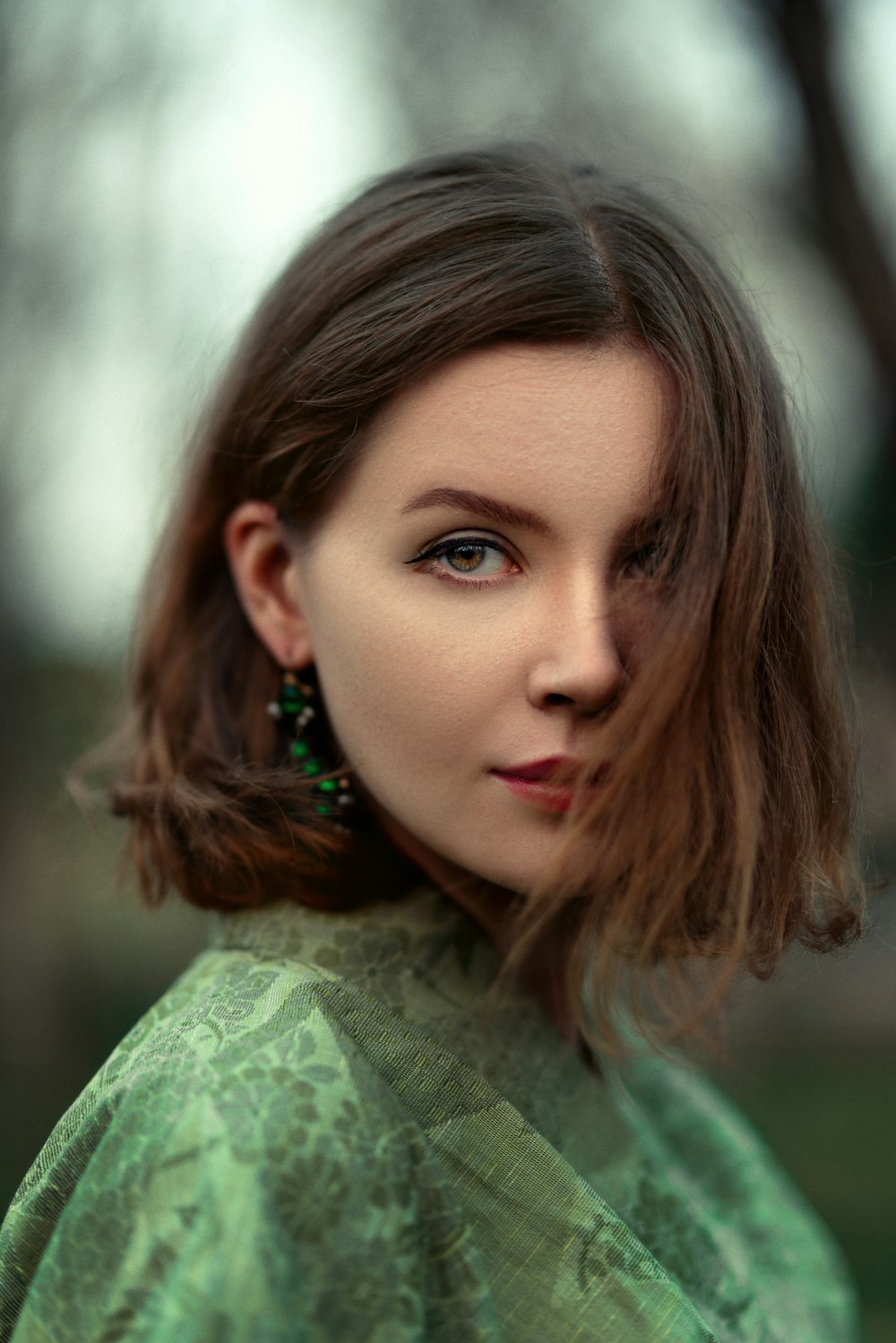 a woman with a green shirt and earrings