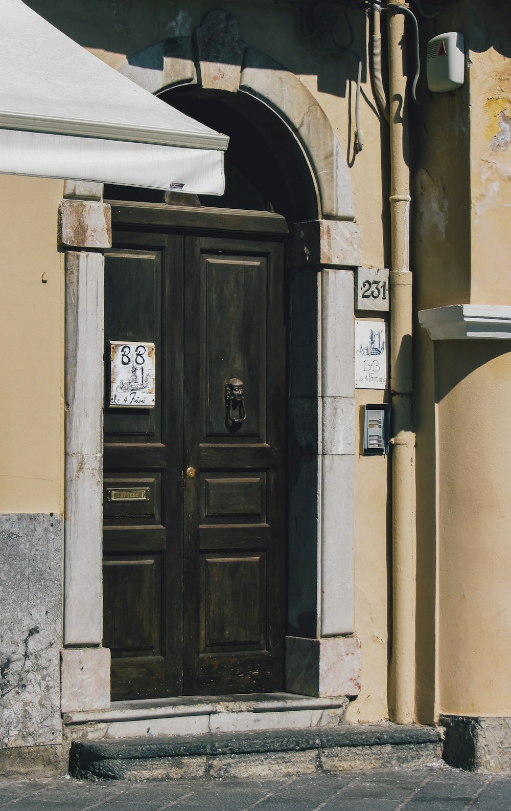 a brown door with a white awning next to a building