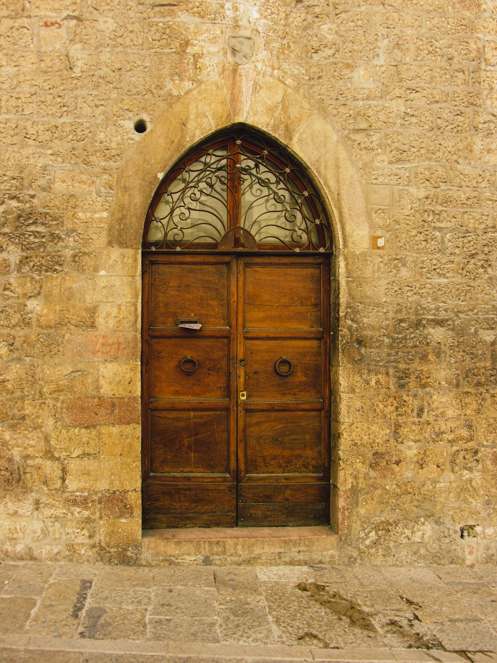 a large wooden door with a window on the side of a building