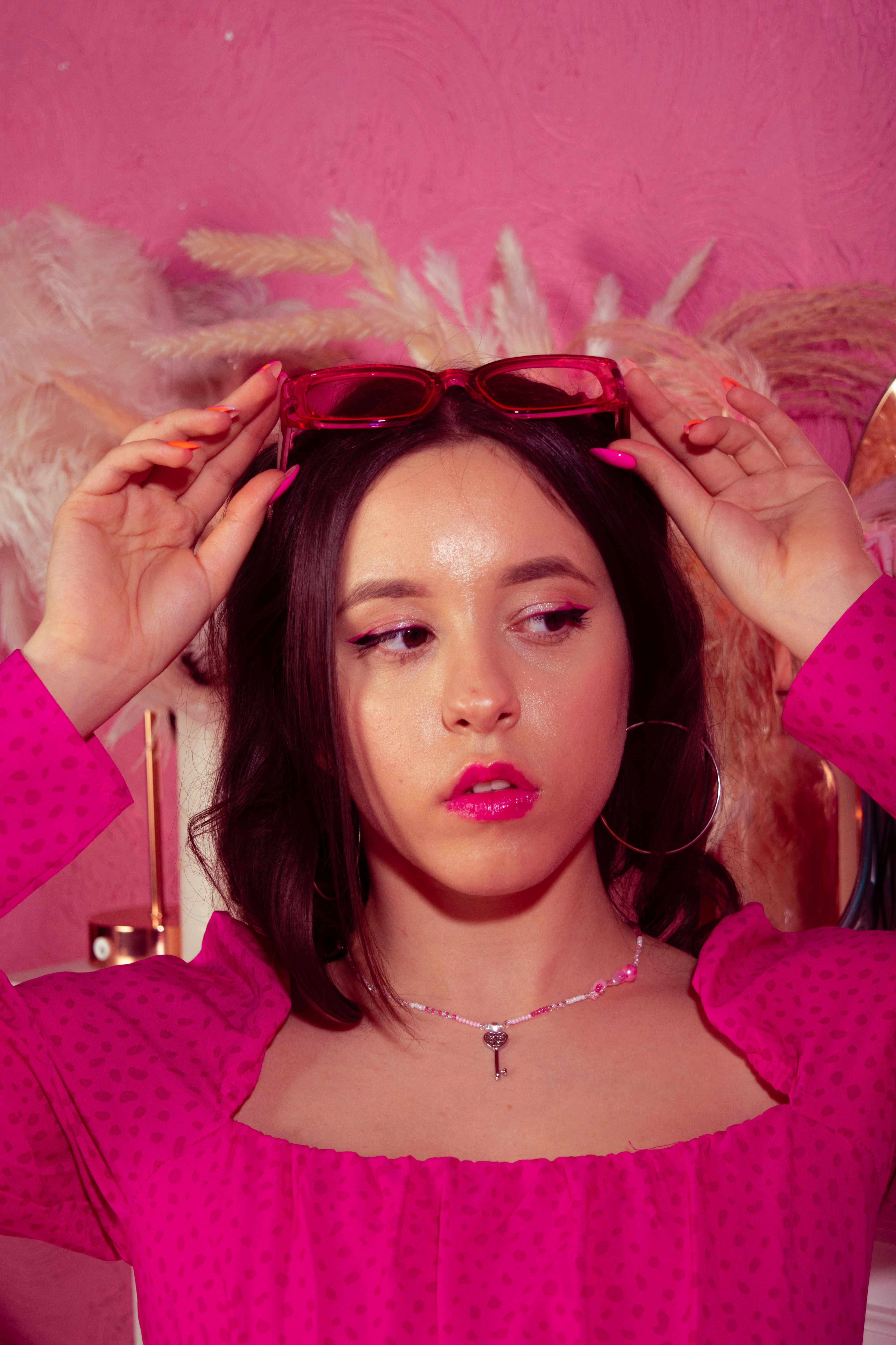 A woman in a pink top with her hands on her head photo – Free Portrait ...