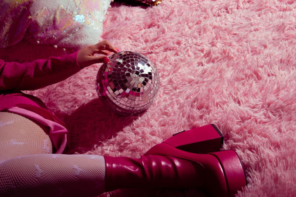 a girl sitting on the floor with a disco ball