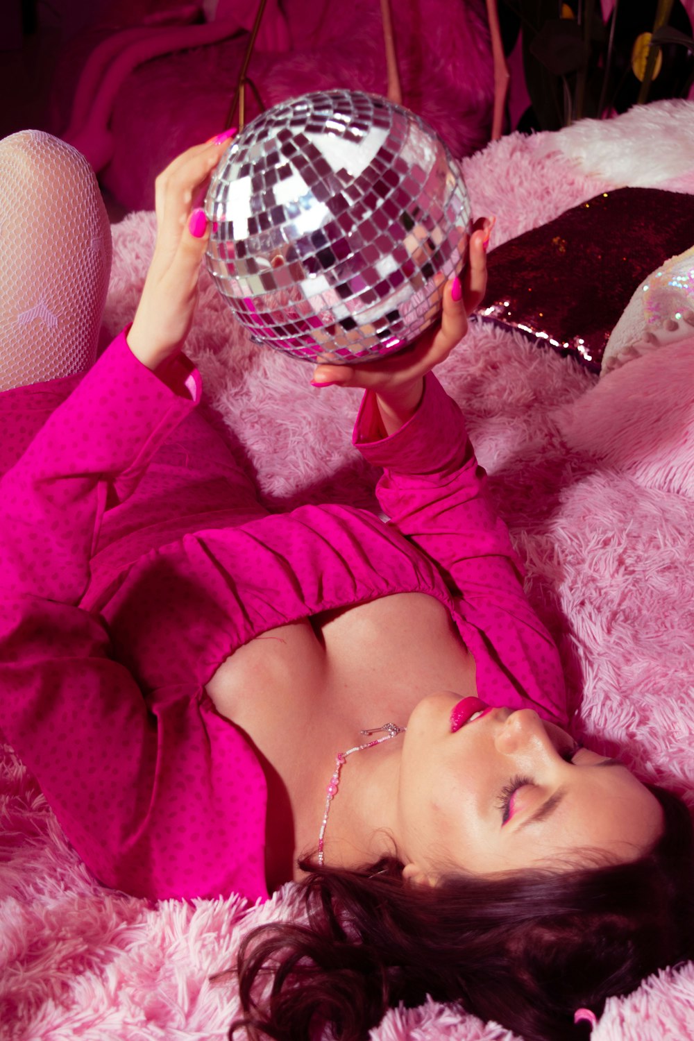 a woman in a pink dress is holding a disco ball