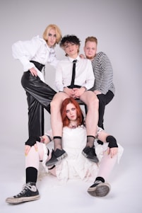 A minimalist editorial photo featuring a diverse group of people wearing eclectic, artful outfits against a clean white backdrop.