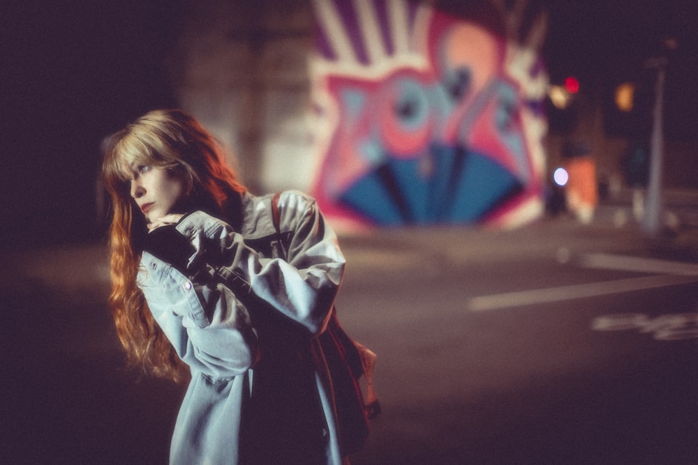 a woman with red hair standing on a street corner