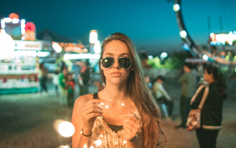 a woman wearing sunglasses holding a sparkle ball