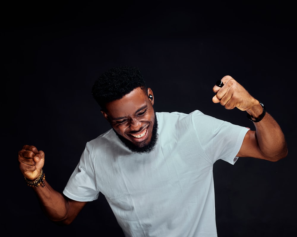 a man in a white t - shirt is holding his fist up