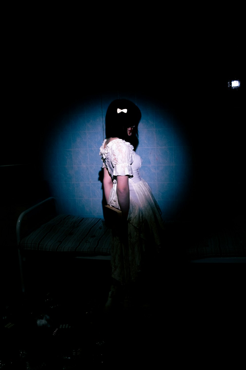 a woman in a white dress standing in a dark room