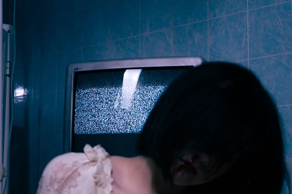 a woman standing in front of a tv in a bathroom