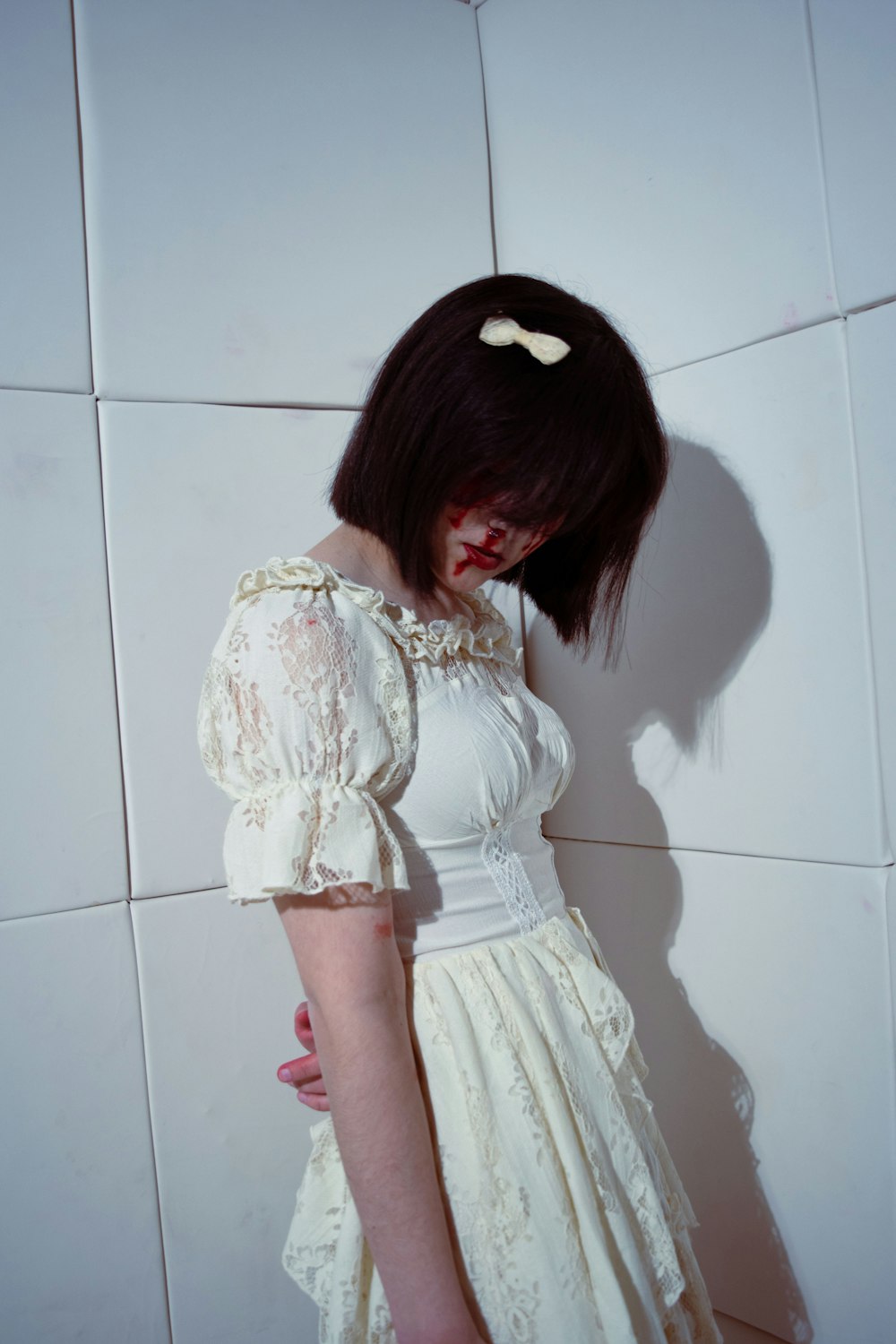 a woman in a white dress standing against a wall
