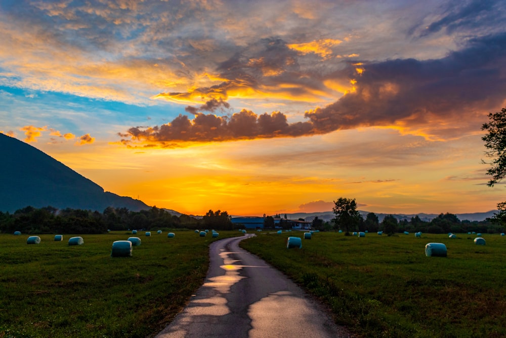 a sunset over a field with bales of hay