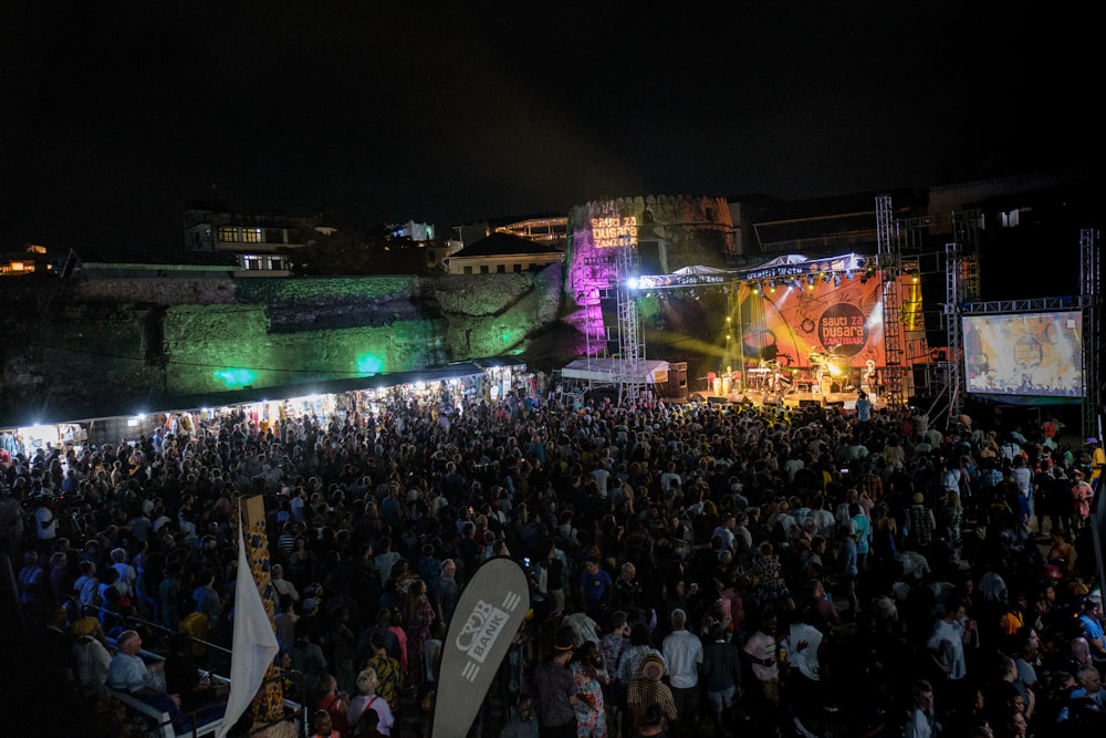 a crowd of people standing around a stage at night