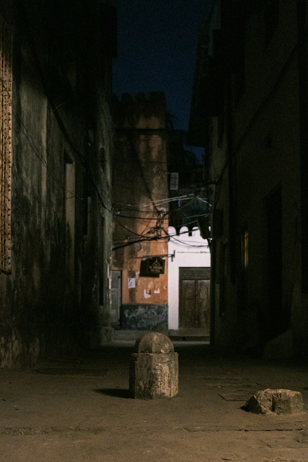 a dark alleyway with a stone ball in the middle