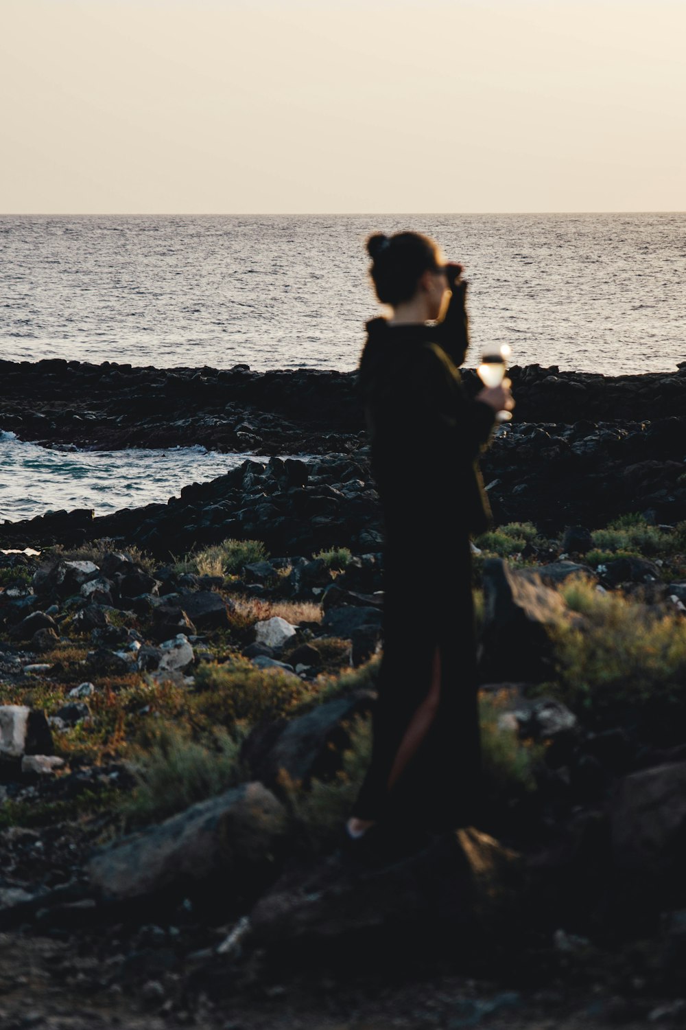 Una donna in piedi sulla cima di una spiaggia rocciosa vicino all'oceano