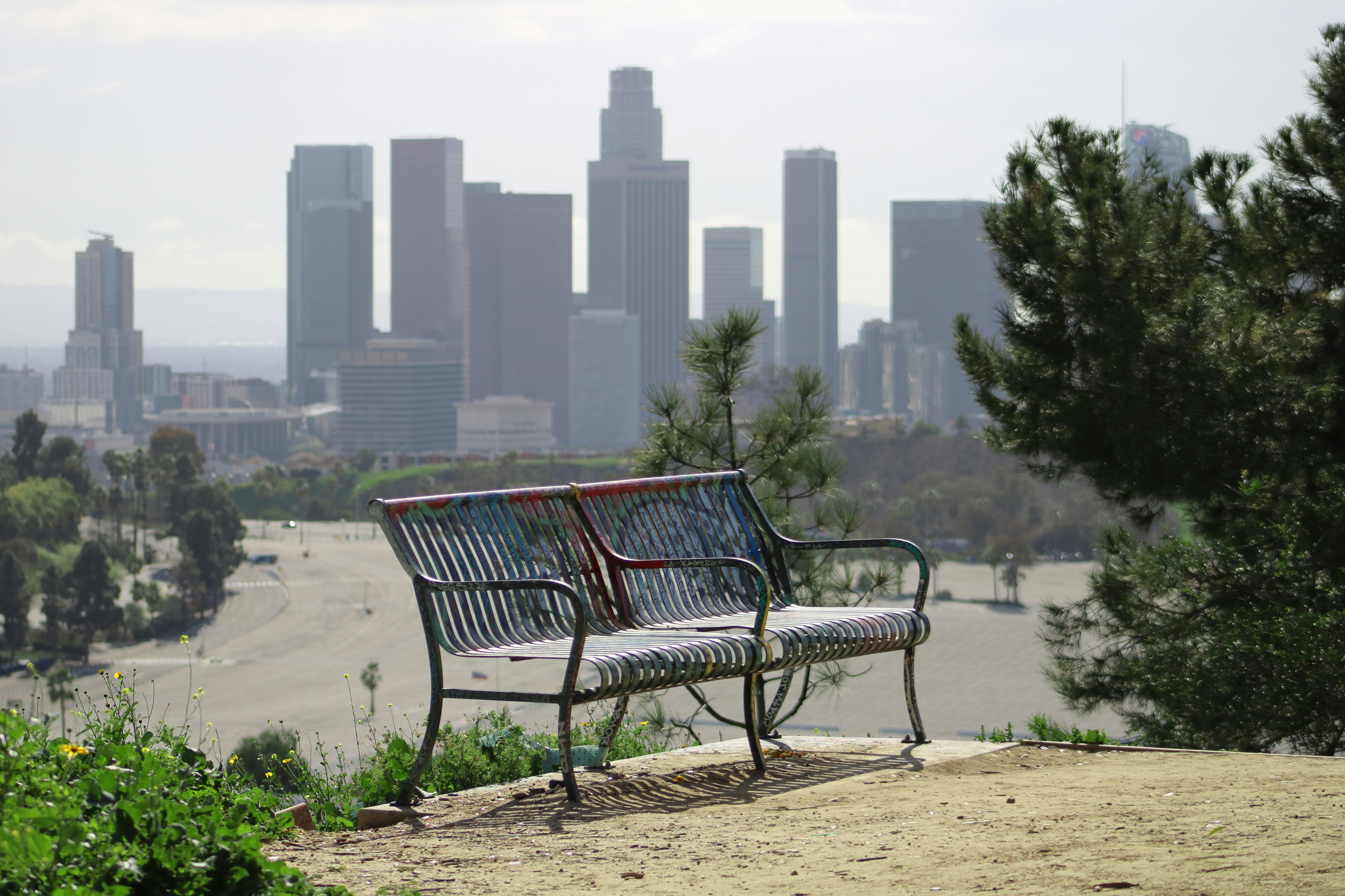 a bench with a city in the background, 