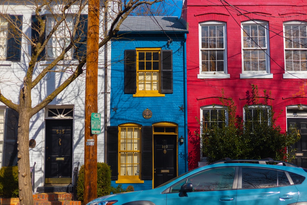 a blue car parked in front of a row of colorful houses