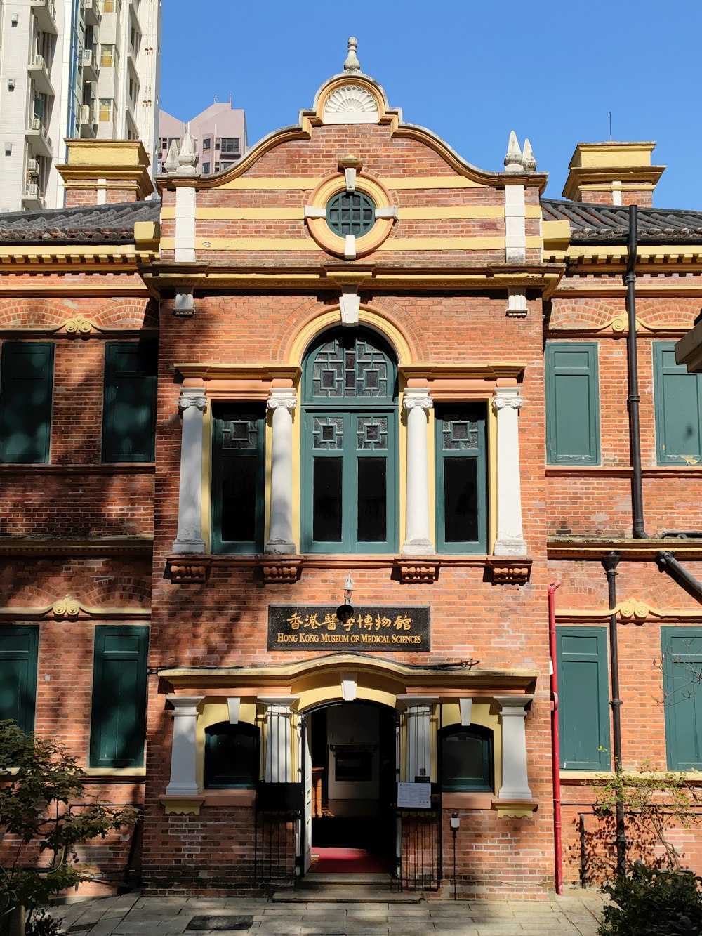 a large brick building with green shutters and a clock