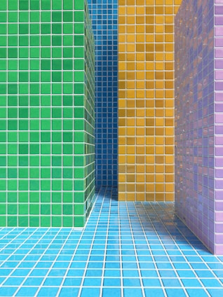 Brightly colored tiled walls and floor create a vivid geometric pattern. The tiles are arranged in blocks of different colors, including green, yellow, blue, and purple, giving a modern and abstract appearance.
