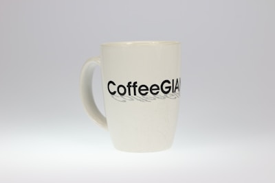 A white ceramic mug with the word 'CoffeeGiant' printed in bold black letters on its surface. The mug is simple and has a smooth, glossy finish.