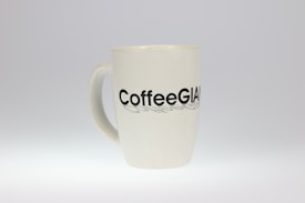 A white ceramic mug with the word 'CoffeeGiant' printed in bold black letters on its surface. The mug is simple and has a smooth, glossy finish.