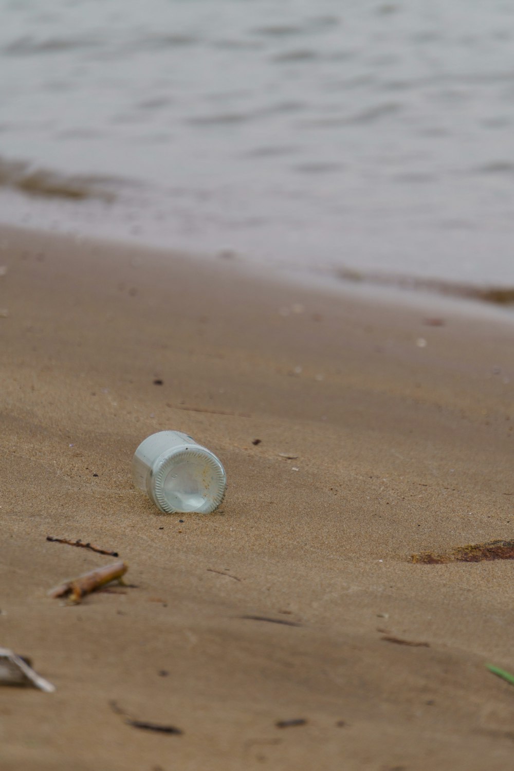 a plastic bottle on a beach with water in the background