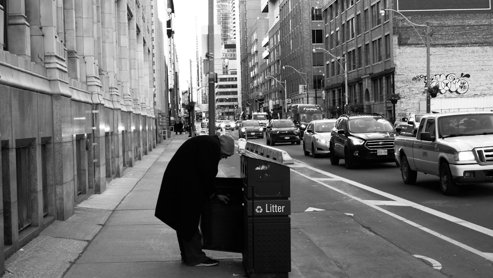 a person standing on a sidewalk next to a trash can