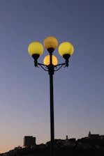 Close-up of a sleek LED street light fixture glowing softly against a twilight cityscape.
