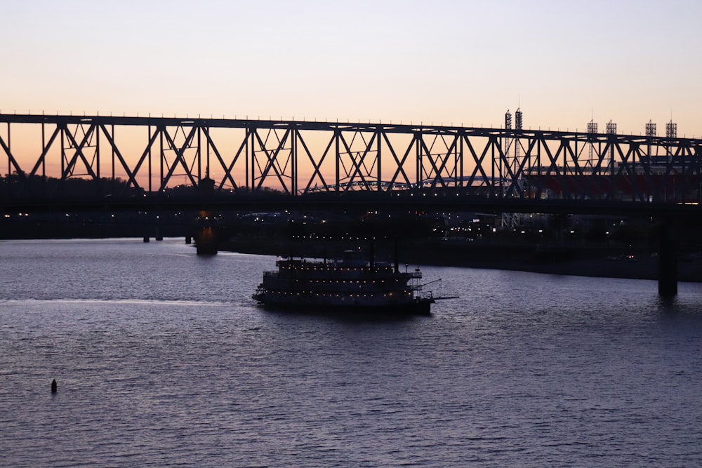 a large boat floating on top of a river under a bridge