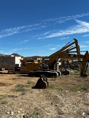 Group of construction machines parked on a gravel surface.