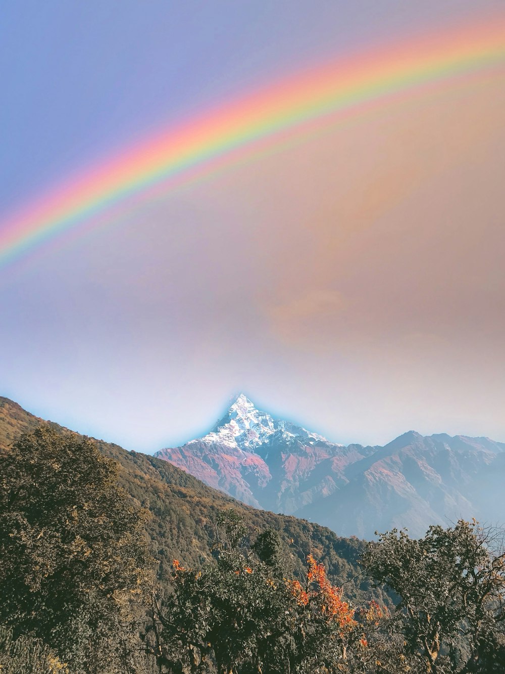 a rainbow appears over a mountain range in the distance