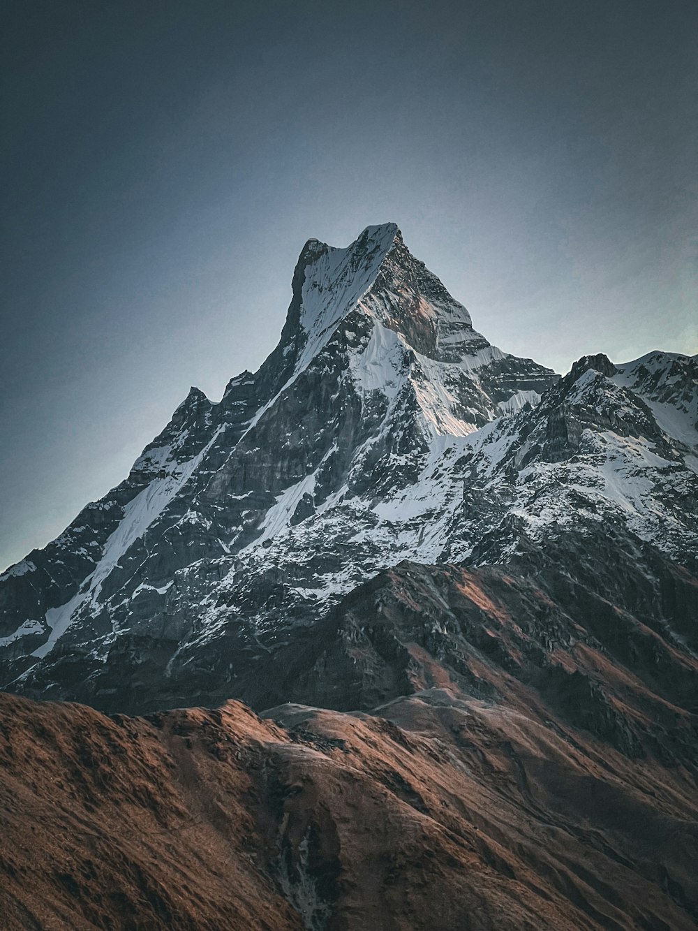 a very tall snow covered mountain under a cloudy sky